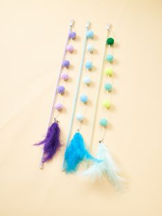 three different colored feathered objects are on a white surface, one is blue and the other is purple