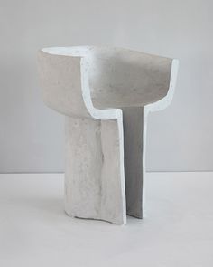 a white sculpture sitting on top of a table next to a gray wall and floor