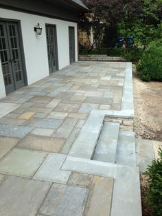 an outdoor patio with steps leading up to the front door and side doors on both sides