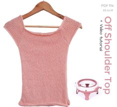 a pink sweater on a wooden hanger next to a measuring cup and an object