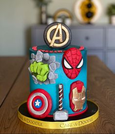 a birthday cake decorated with the avengers symbol and other things on it's side