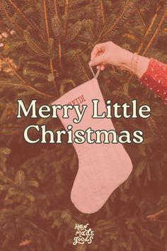 a hand holding a christmas stocking with the words merry little christmas written on it