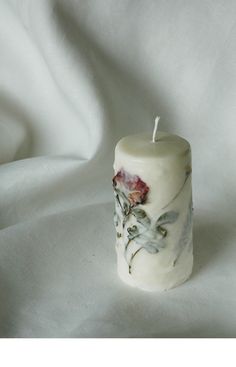 a white candle with flowers painted on it