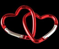 two red heart shaped metal objects against a black background