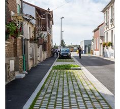 a car parked on the side of a road next to a sidewalk with grass growing in it