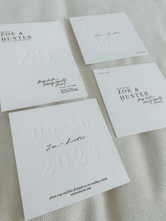 four wedding cards with the names and date printed on them are laying on a bed