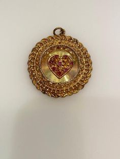 Vintage 14k yellow gold ruby heart round filigree disc with rope edge charm. The charm is 14.98 grams of gold. Antique Gold Jewelry With Round Pendant Charms, Collectible Gold Jewelry With Heart Charm, Victorian 14k Gold Jewelry For Valentine's Day, Victorian Yellow Gold Jewelry For Valentine's Day, Valentine's Day Engraved Medallion Jewelry, Collectible Yellow Gold Necklace With Heart Charm, Yellow Gold Heart Charm Round Pendant, Yellow Gold Filigree Jewelry For Valentine's Day, Victorian 14k Gold Heart-shaped Jewelry