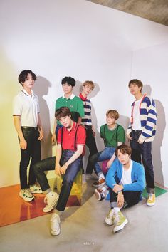 a group of young men sitting next to each other in front of a white wall