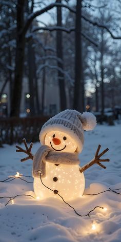 a snowman with a hat and scarf on in the snow surrounded by christmas lights