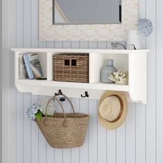 a white shelf with baskets and hats on it next to a wall mounted mirror in a bathroom