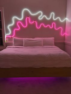 a bed with white sheets and pink lights on the headboard, in a bedroom