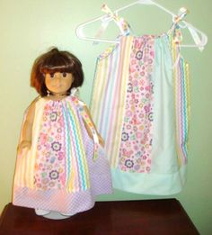 a doll is standing next to a dress on a table