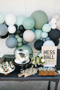 a table topped with cakes and desserts next to balloons