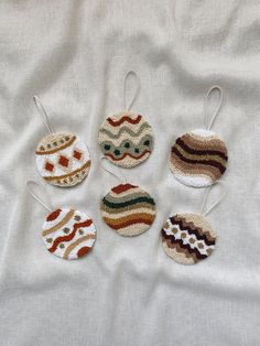 six crocheted ornaments are arranged on a white sheet, each with different designs