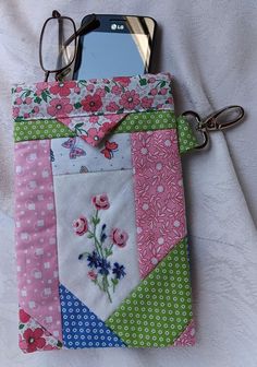 a pink and green patchwork purse with eyeglasses resting on it's side