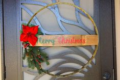 a merry christmas sign hanging on a door with a wreath and poinsettis