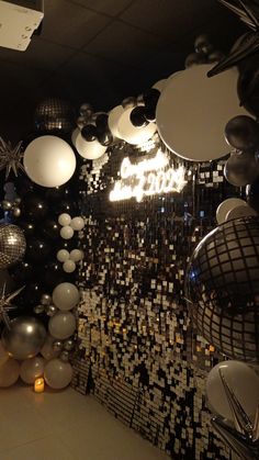 balloons and disco balls are hanging from the ceiling in an office space with black and white wallpaper