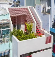 an apartment building with red and white balconies on the roof, next to other buildings