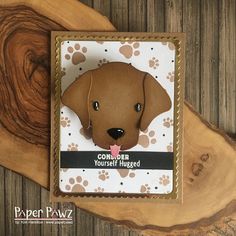 a card with a dog's face and paw prints on it, sitting on top of a piece of wood