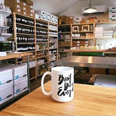 a coffee mug sitting on top of a wooden table in a room filled with shelves