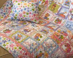 a bed with colorful quilts and pillows on it's sides, along with two pillow cases