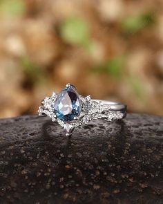 a blue and white diamond ring sitting on top of a rock