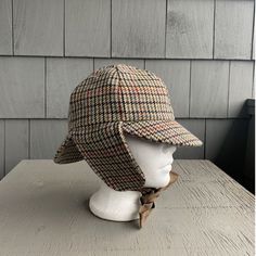 a hat is sitting on top of a mannequin's head, next to a wall