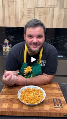 a man sitting at a table with a bowl of macaroni and cheese in front of him