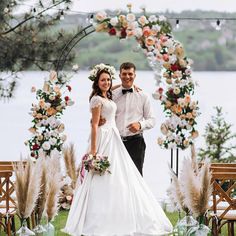 a bride and groom standing in front of an arch decorated with flowers