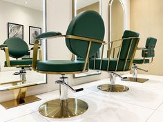 two green chairs sitting in front of a mirror on top of a white countertop