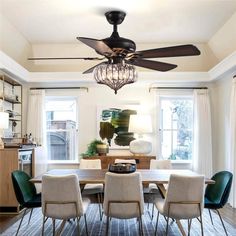 a dining room table with chairs and a ceiling fan in the middle of the room