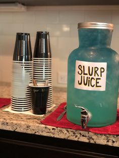 there is a blue jar with a sign on it sitting on the kitchen counter next to cups