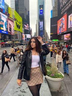 a woman is walking down the street with her hand on her head and looking at the camera