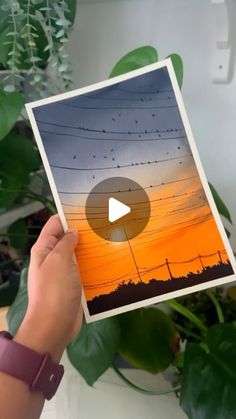 someone holding up an image with the sun setting in the background