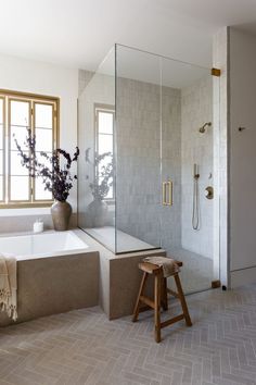 a bathroom with a tub, shower and stool next to the bathtub is shown