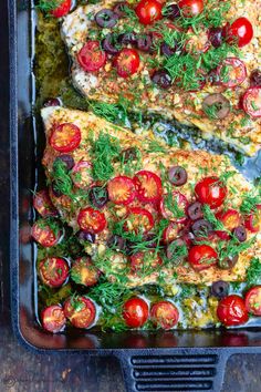 two pieces of fish covered in tomatoes and herbs