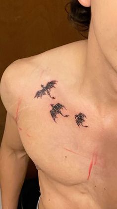 a man with a tattoo on his chest that has three bats flying through the air