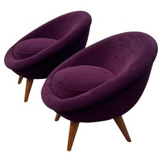 two purple chairs sitting next to each other on top of a white surface with wooden legs