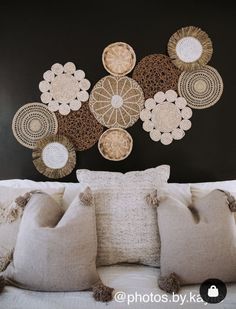 a bed topped with lots of pillows and decorative wall hangings above it's headboard