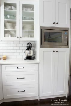 the kitchen cabinets are white and have glass doors on one side, while the rest of the cabinet door is black