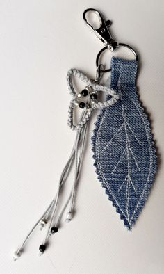 a pair of scissors are attached to a leaf shaped keychain that is made out of denim