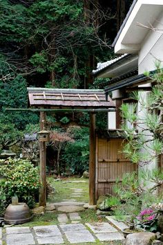 an outside view of a house with trees and plants in the back yard, next to a stone path