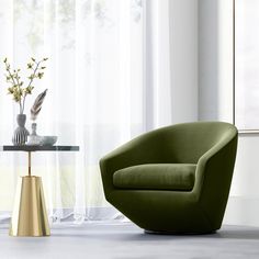 a green chair sitting next to a table with vases on it