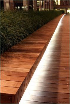 a bench sitting on top of a wooden floor next to tall grass