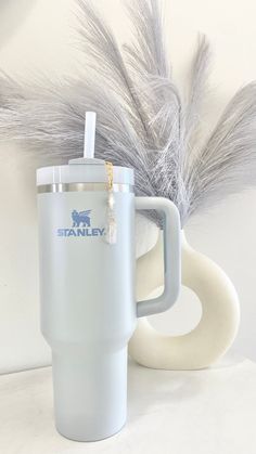 a white coffee cup with a straw in it next to a gray and white mug