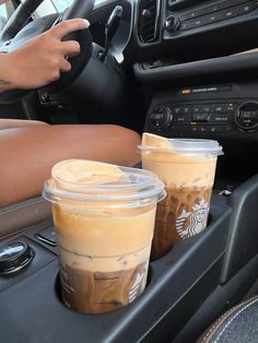 two cups of iced coffee sitting on the dashboard of a car