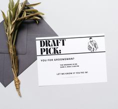 an envelope with a business card on it next to a dried plant and some gray envelopes