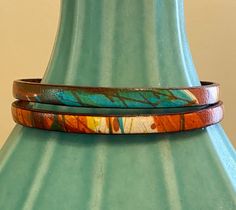 "This leather cord is beautifully finished in streaks of orange, turquoise, and beige ... much like a western sunset. The color variations are unique and organic and no two bracelets are exactly the same. Finished with a charm set of genuine turquoise with a small round of amber on top, you'll love the attention to detail. Best part: you can choose from a silver Om charm or a lotus flower! **May 12 update: currently the lotus flower is available. The aesthetic is both Boho and Western Chic and w Western Sunset, Turquoise Wrap Bracelet, Om Charm, Pearl Cuff Bracelet, Orange Turquoise, Hippie Bracelets, Western Chic, Red Moon, Boho Leather