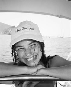 black and white photo of smiling woman in boat with hat on head looking out over water