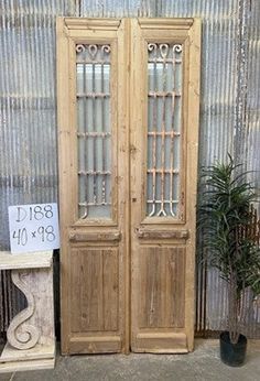 two wooden doors sitting next to each other in front of a wall with a sign on it